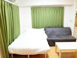 uma cama e um sofá num quarto com cortinas verdes em Tsunoya em Tóquio