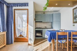 una cocina con armarios azules y una mesa con sillas en Villetta Crepaz, en Canazei
