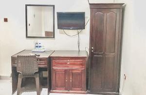 a desk with a chair and a television and a cabinet at Hotel Aida Syariah Mitra RedDoorz in Samarinda