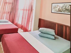 a bedroom with two beds with red and blue pillows at Hotel Aida Syariah Mitra RedDoorz in Samarinda