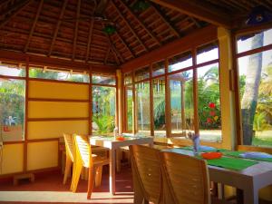 a dining room with tables and chairs and windows at SAMBODHI YOGA RETREAT in Alleppey