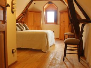 a bedroom with a bed and a window and a chair at Maison O'Galop in Beynac-et-Cazenac