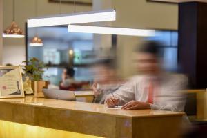 a man sitting at a counter in a restaurant at Almond Hotel Sothearos in Phnom Penh