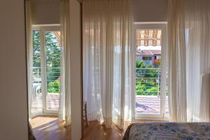 a bedroom with white curtains and a large window at Apartment Maria in Malinska