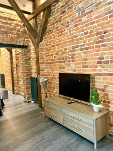 a brick wall with a flat screen tv on a wooden cabinet at Apartamenty Młyńska 4 in Gliwice