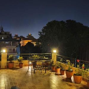 a patio with tables and chairs and potted plants at night at Butsugen in Kathmandu