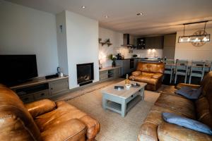 a living room with leather couches and a fireplace at Dartmoor Cottage in Merris