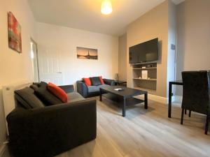 a living room with a couch and a table and a television at Ruskin Place by SG Property Group in Crewe
