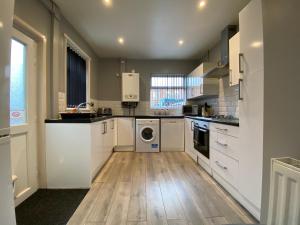 a kitchen with white appliances and a wooden floor at Ruskin Place by SG Property Group in Crewe