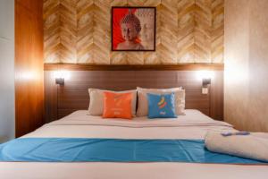un letto con cuscini arancioni e blu in una stanza di Sans Hotel Ekkon Yogyakarta by Reddoorz a Ngabean