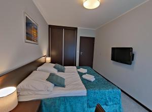 a bedroom with a large bed with a flat screen tv at Apartament przy hotelu Aquarius in Kołobrzeg