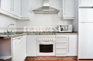 Biała kuchnia z kuchenką i kuchenką mikrofalową w obiekcie Apartamentos Terrasol AZUCARERA ATICO I w mieście Torre del Mar