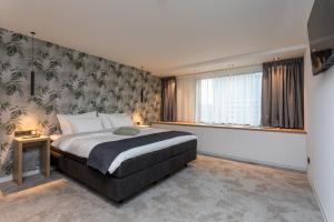 1 dormitorio con cama grande y ventana grande en Hotel de Rousch, en Heerlen