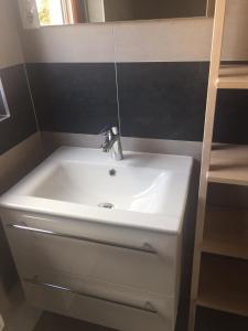 lavabo blanco con grifo en el baño en Kazinczy Apartman, en Balatonalmádi