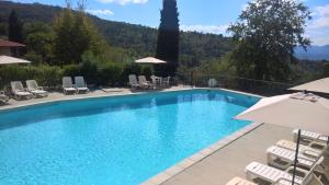a swimming pool with chairs and umbrellas at Residence Casa Lama in Castelfranco di Sopra