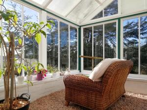 Un invernadero con una silla de mimbre en una habitación con ventanas. en Woodlands, Teignmouth, en Teignmouth
