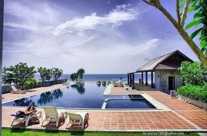 una piscina con sillas y el océano en el fondo en Khanom Beach Residence Sea & Mountain View - 1 Bedroom, en Ban Na Dan