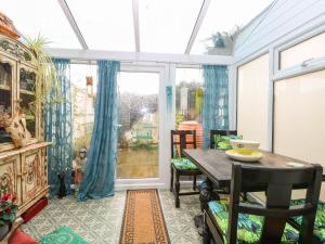 einen Wintergarten mit einem Tisch, Stühlen und einem Fenster in der Unterkunft 21 Florence Road in Lowestoft