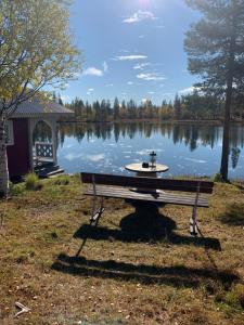 a park bench sitting in front of a lake at Wilderness in off-grid cabin in Lapland in Nattavaara