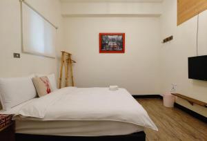 1 dormitorio con 1 cama blanca grande y TV en OC Hostel, en Tainan