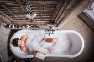 a man is laying in a bath tub at Berry House in Vigolo Vattaro