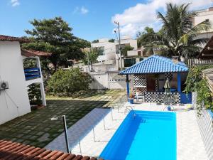 a blue swimming pool with a gazebo next to a house at Pousada do caju in Serra