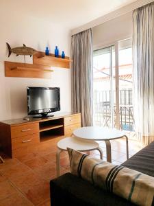 a living room with a bed and a tv and a table at Apartamentos Nerjaluna in Nerja