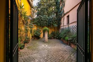 an entrance to a courtyard with plants and trees at La Scala in Rome