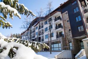 Un edificio de apartamentos con nieve en el suelo. en Borovets Green Hotel, en Borovets