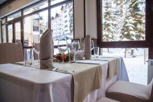 a table with white table cloths and wine glasses at Borovets Green Hotel in Borovets
