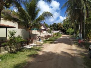 un camino de tierra frente a una casa con palmeras en Chalés Caribe brasileiro - Chalé 1, en Maragogi