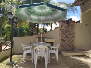 uma mesa e cadeiras sob um guarda-sol num pátio em Chalés Caribe brasileiro - Chale 2 em Maragogi