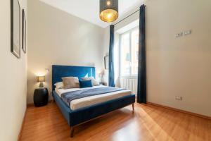 a bedroom with a blue bed and a large window at Rione Prati Apartment - MM Lepanto in Rome