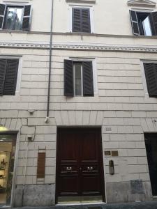 a white brick building with a brown door and windows at Frattina FF italian suites in Rome