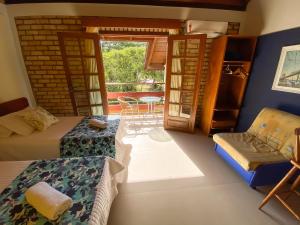 a room with beds and a balcony with a table at Pousada Portal Sul in Florianópolis