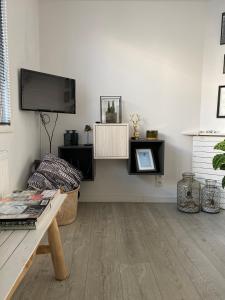 een woonkamer met een bank en een tv aan de muur bij Huisje 16 in Noordwijk aan Zee