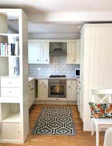 a kitchen with white cabinets and a rug at Charming Cottage & Garden - central Brighton! in Brighton & Hove