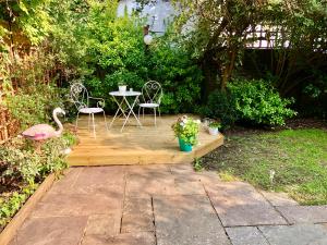 une terrasse en bois avec une table, des chaises et un cygne dans l'établissement Charming Cottage & Garden - central Brighton!, à Brighton et Hove