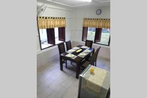 ein Esszimmer mit einem Tisch, Stühlen und Fenstern in der Unterkunft De RhuMaa Homestay in Kuala Terengganu