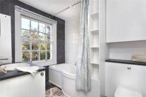 Charming Cottage & Garden - central Brighton! في برايتون أند هوف: حمام أبيض مع حوض استحمام ونافذة