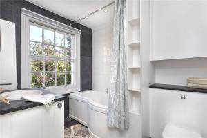 ein weißes Badezimmer mit Badewanne und Fenster in der Unterkunft Charming Cottage & Garden - central Brighton! in Brighton & Hove