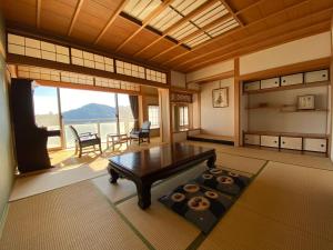 a living room with a table and a large window at Atami Onsen Guest House Megumi in Atami