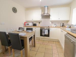 a kitchen with a table with chairs and a microwave at Stable Cottage Llandudno in Llandudno