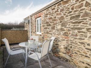 a table and chairs on a patio with a stone wall at Stable Cottage Llandudno in Llandudno