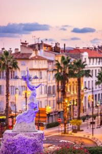 una estatua en medio de una ciudad con edificios en Chez Tom - au pied des musées, en Grasse