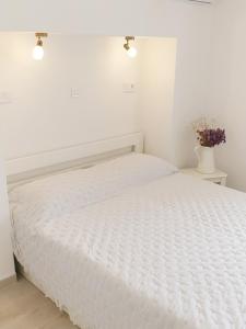 a white bedroom with a bed with a white bedspread at Rooms in Primošten
