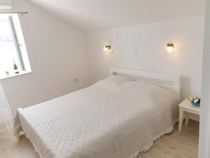 a white bedroom with a bed and a window at Rooms in Primošten