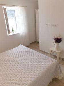 a white bedroom with a large bed with a window at Rooms in Primošten