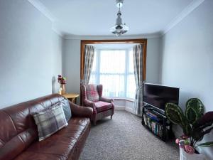 uma sala de estar com um sofá de couro castanho e uma cadeira em Purple Cloud Cottage em Portsmouth
