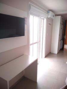 a living room with a white bench and a tv at Hotel Jardim do Mar in Torres